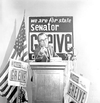 R.R. 'Bob' Greive at a podium surrounded by re-election signs